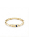 May include: A gold ring with a small, round, dark blue gemstone set in a smooth, elongated bezel. The ring has a simple, elegant design, perfect for everyday wear. The band is a polished gold color.