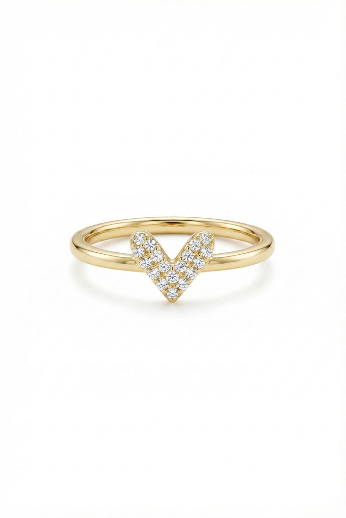 May include: A gold ring with a heart-shaped design. The heart is formed by small, sparkling diamonds set in a V-shape. The band is a smooth, polished gold. The ring is set against a white background.