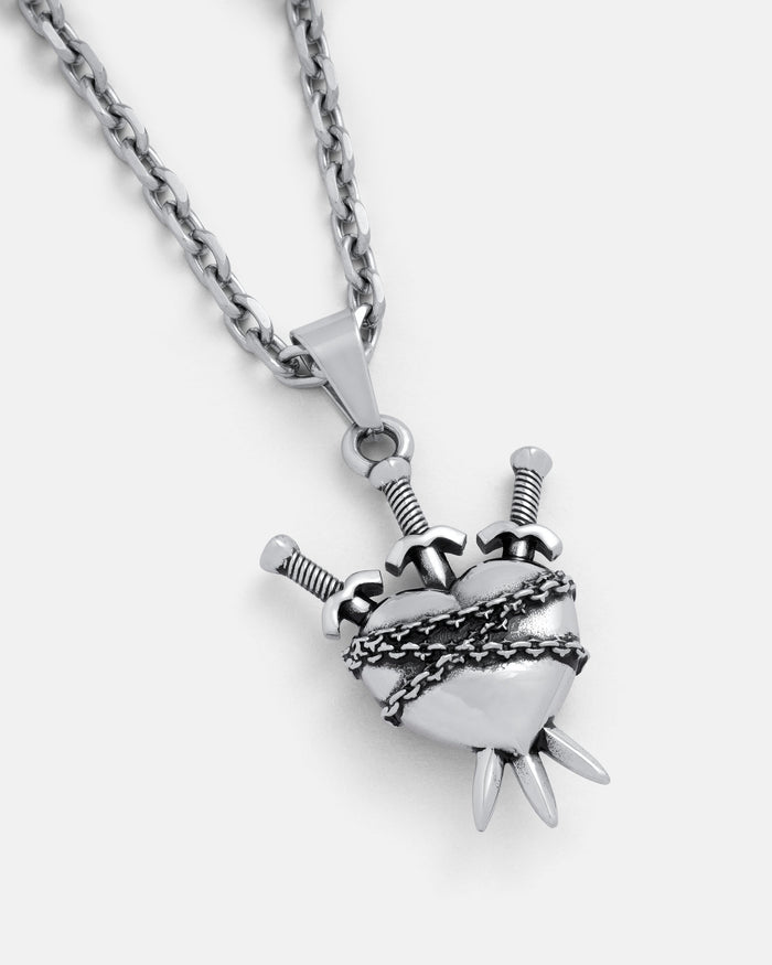 The "3 of Swords" Pendant is a silver necklace with a heart wrapped in barbed wire, pierced by three swords, and features two bottom spikes on a thick chain—a striking tarot-themed heartbreak necklace.