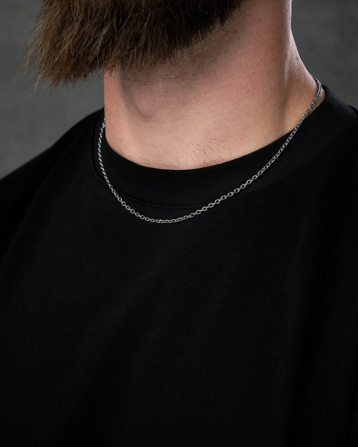 A close-up of a person with a brown beard wearing the 3mm Cable Chain and a plain black T-shirt. Only their lower face and neck are shown; the chain is non-tarnish.