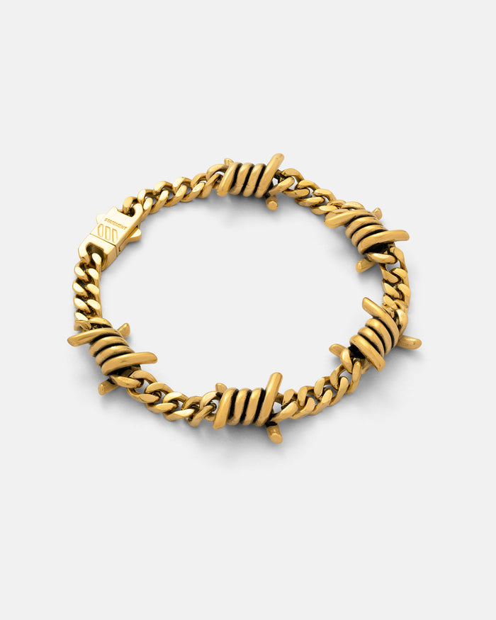 Gold 6mm barbed wire bracelet by statement collective on grey background.