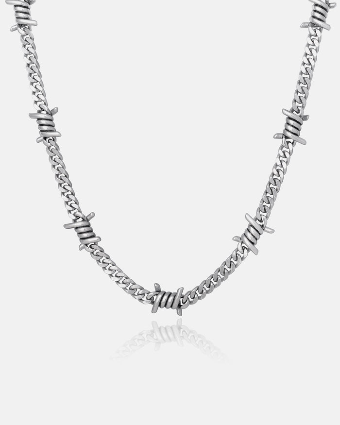 The 6mm Barbed Wire Cuban Chain features silver barbed wire details evenly spaced along the chain, creating a striking statement piece, shown against a plain white background.