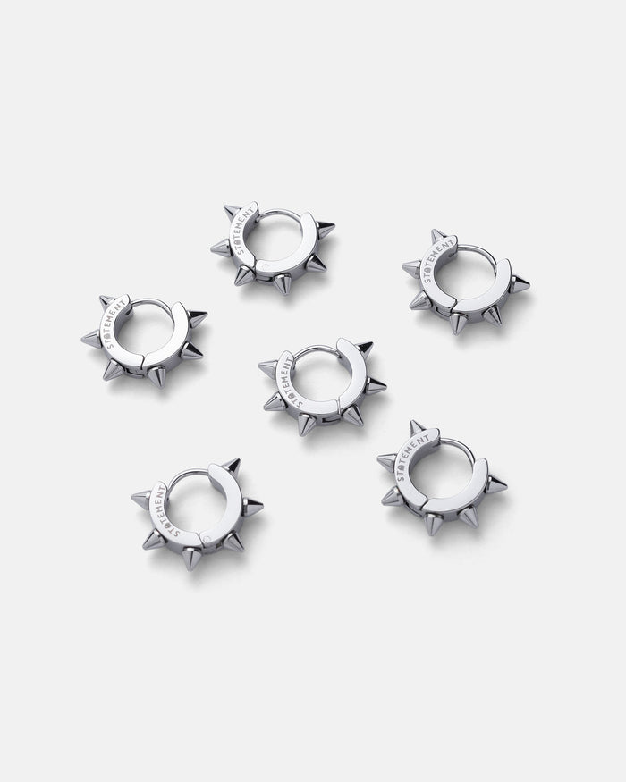 Six 8mm Spiked Hoop Earrings in a silver color are arranged in two rows on a plain light gray background. Each punk hoop earring features engraved text on the smooth stainless steel band section.