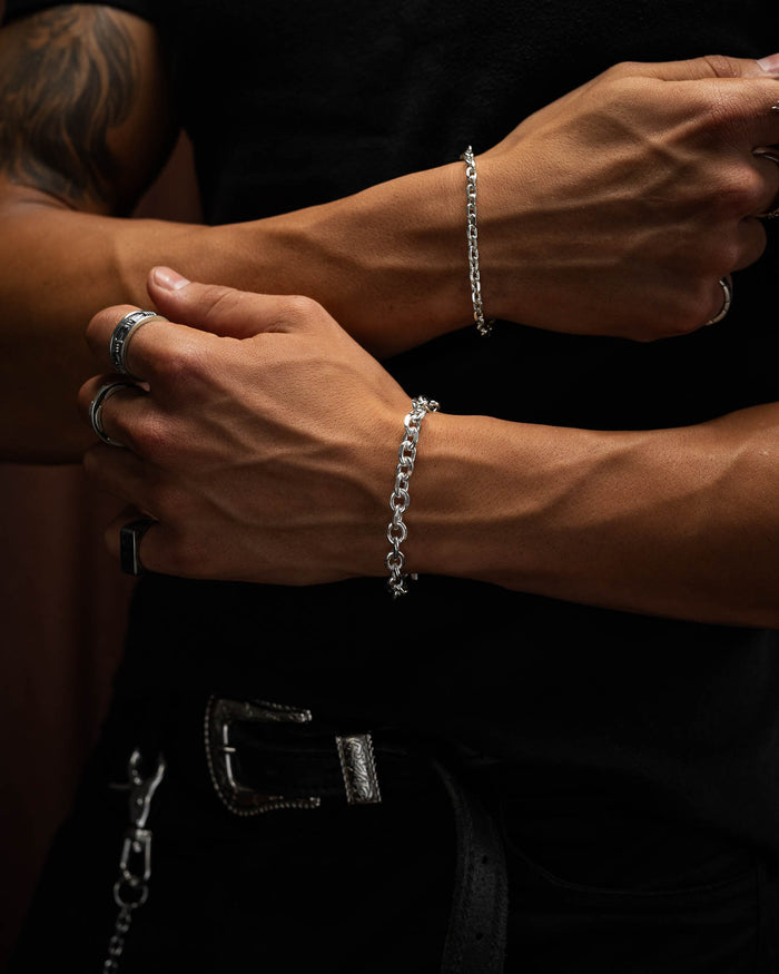 male model arms crossed over his black shirt,  showing the 8mm cuban link bracelet in 925 sterling silver. against brown velvet backdrop.