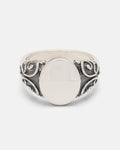 A handcrafted 925 Sterling Silver Mini Oval Scroll Signet Ring by Statement Collective, featuring a smooth, flat oval center and ornate, swirling scroll designs along the band, photographed against a plain white background.