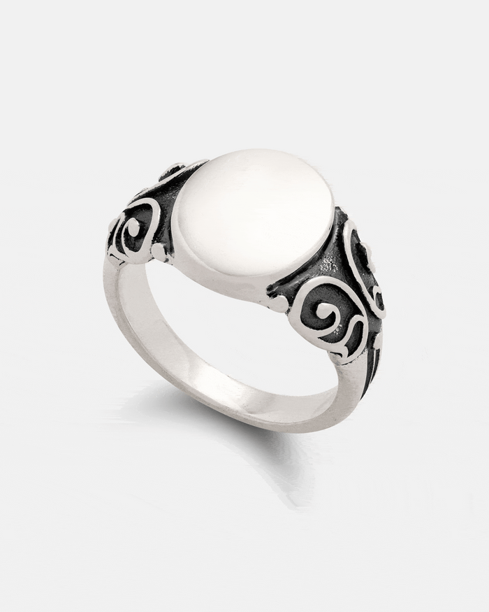 The Statement Collective 925 Sterling Silver Mini Oval Scroll Signet Ring features a smooth, oval flat top and intricate black scrollwork detailing on the band, displayed on a plain white background.