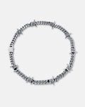 The 9mm Barbed Wire Cuban Chain features twisted silver barbed wire sections woven along a flat cuban link. Styled in a circle on a plain light background, this statement necklace stands out with its bold, unique design.