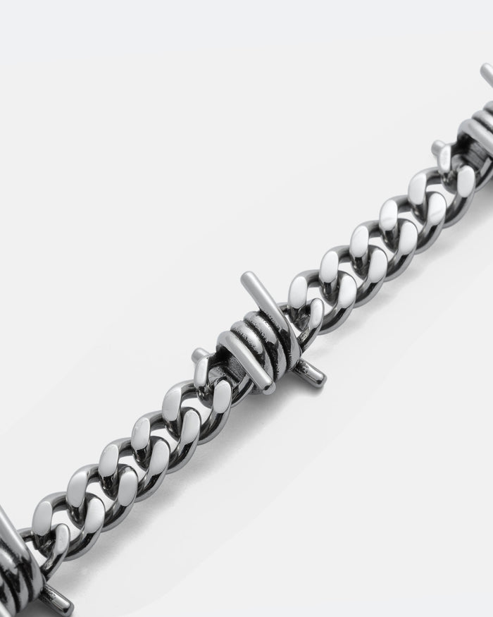 Close-up of the 9mm Barbed Wire Cuban Chain bracelet, featuring a curb link design with evenly spaced metallic barbed wire accents.