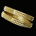 Gold and pearl bangles on a black stand with 'Saheli' branding.