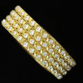 Gold bracelet with clear stones on a black cushion, branded 'Saheli'.