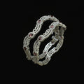 Pair of silver bangles with gemstones on a dark background, branded 'Saheli'.