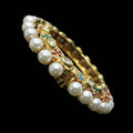 Jewelry bracelet with pearls and gemstones on a gray cushion