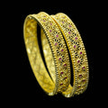 Gold bangles with intricate designs on a dark background