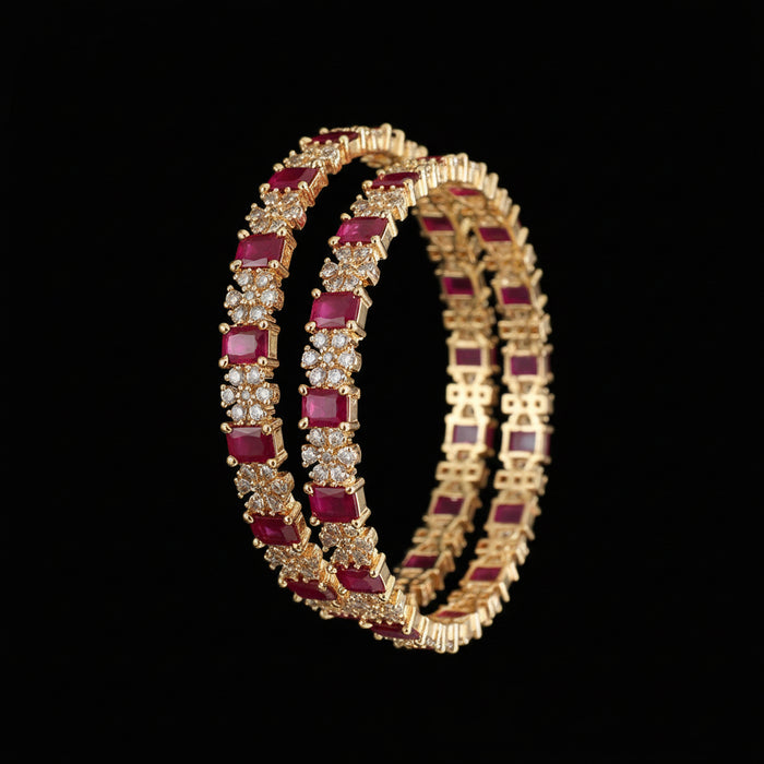Gold bangles with red gemstones on a dark background
