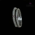 Silver bangles with purple stones on a black stand, branded 'Saheli'.