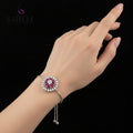 Silver bracelet with pink gemstone on a gray background, featuring the brand 'SAHELI'.