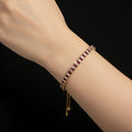 Gold bracelet with red and white stones on a black background