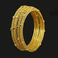 Gold bangles on a dark background with 'Saheli' brand logo.