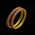 Gold and pink bangles on a black fabric background with 'SAHELI' branding.