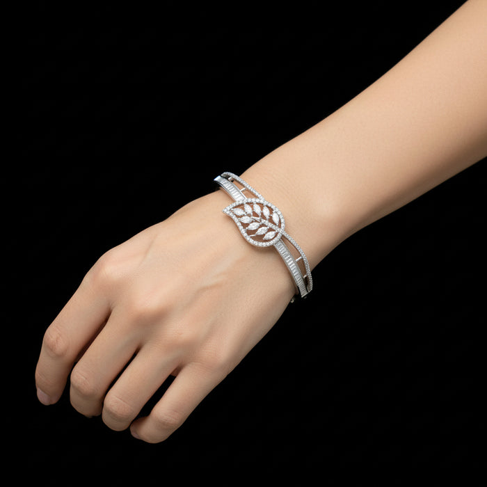 Silver leaf-shaped bracelet on a gray cushion with a dark background