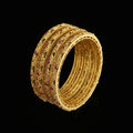 Gold bangles with red stones on a gray background, featuring the brand 'Saheli'.