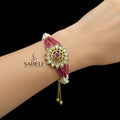 Decorative bracelet with pink and white beads and gold accents on a dark background, featuring the brand 'SAHELI'.