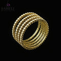 Gold bracelets on a black stand with 'SAHELI' branding on a gray background
