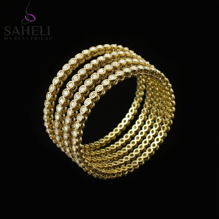 Gold bracelets on a black stand with 'SAHELI' branding on a gray background
