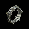Silver bangles with intricate designs on a gray stand, branded 'Saheli'.