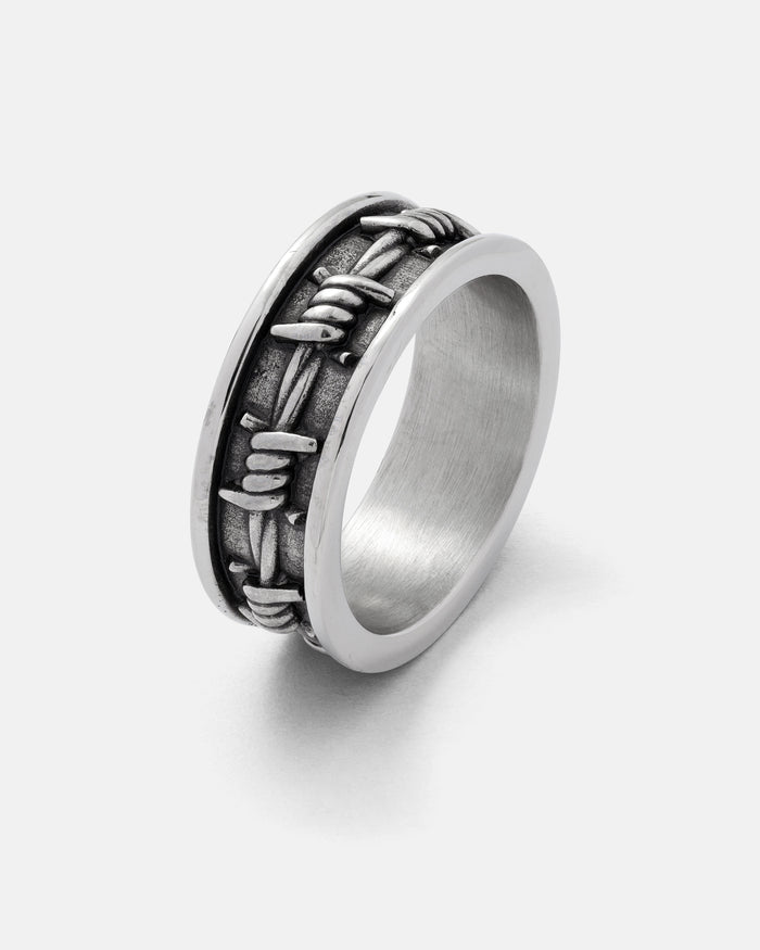 The Barbed Wire Ring by Statement Collective is crafted from durable 316L stainless steel, showcasing a raised barbed wire design that encircles the band, and is displayed against a plain white background.