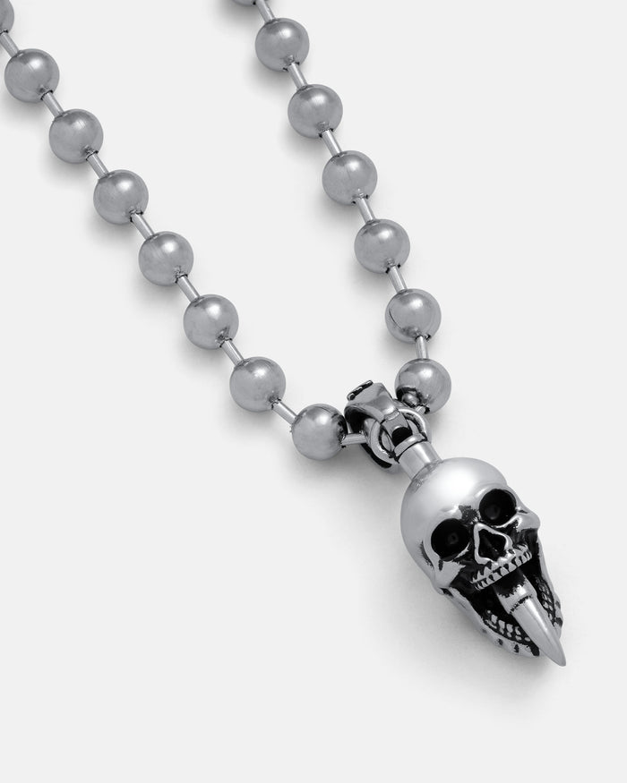 A close-up of the "Bite The Bullet" Pendant—a silver beaded designer necklace with a metallic skull pendant featuring a long, pointed lower jaw—set against a plain white background.