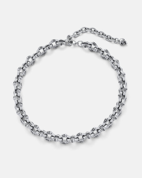 The "Boneyards" Skull Chain is a stainless steel necklace with interlinked skull-shaped links, an adjustable clasp, and extension chain, shown on a plain light background.