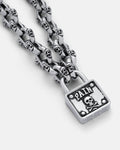 The "Boneyards" Skull Padlock Chain features bold skull-shaped links on a 12mm cable chain and a square pendant engraved with PAIN and a skull and crossbones motif.