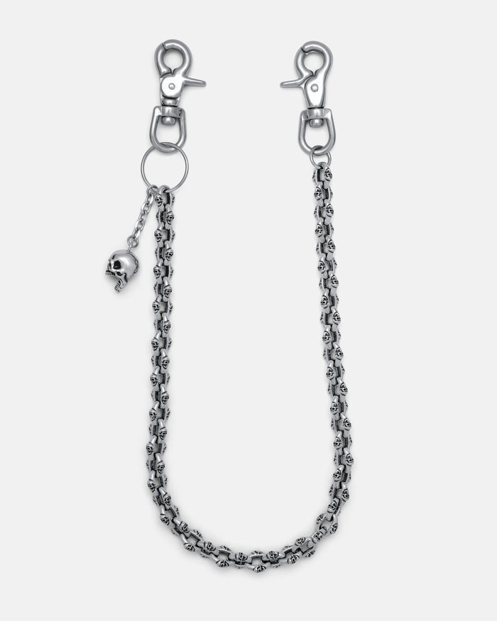 The "Boneyards" Skull Wallet Chain is a silver stainless steel accessory with two lobster clasps, small skull details along the chain, and a dangling skull charm near one clasp, shown on a plain light background.