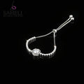 Silver bracelet with heart-shaped clasp on a dark background, featuring the brand 'SAHELI'.