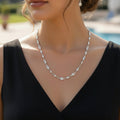 Silver necklace on a black mannequin with 'SAHELI' branding.
