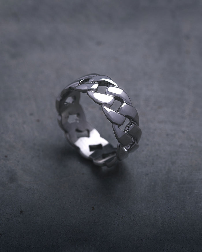 The Cuban Link Ring, featuring a chunky silver interlocking chain design, is displayed upright on a dark, textured surface.