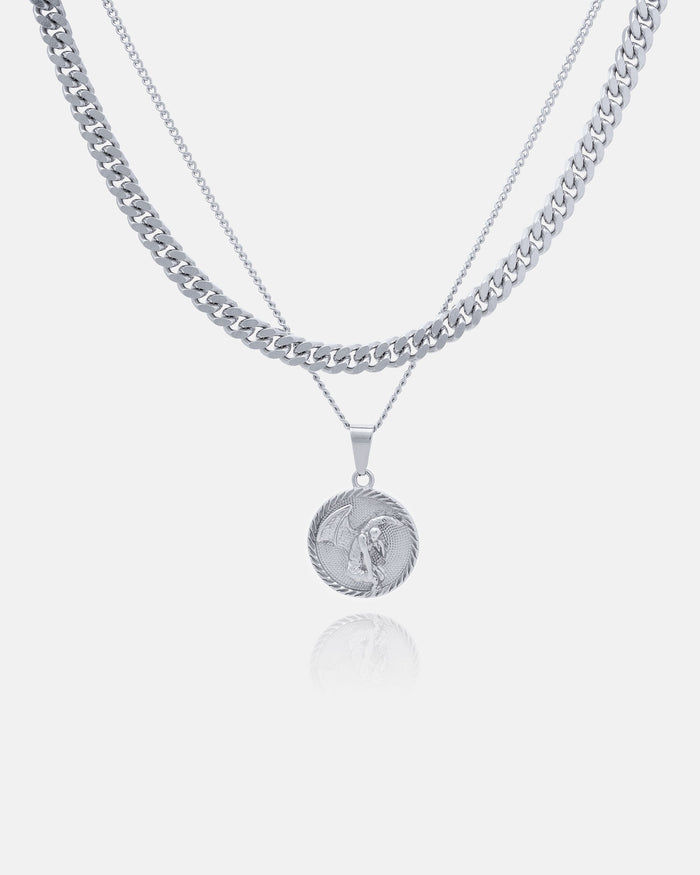 The Cuban Set (Custom Pendant Choice) includes three layered silver necklaces: a thick Cuban link chain, a thin chain, and a thin chain with your choice of engraved round pendant, all displayed on a white background.