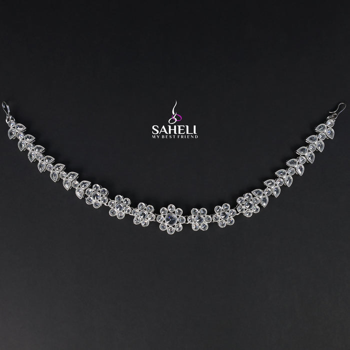 Silver necklace with floral design on a black background, featuring the brand 'Saheli'.