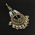 Decorative pendant with pearls and green stones on a black background