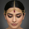 Gold necklace with red gemstones on a dark background, featuring the brand 'SAHELI'.