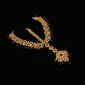 Ornate necklace with red stones on a dark background, featuring the brand 'Saheli'.