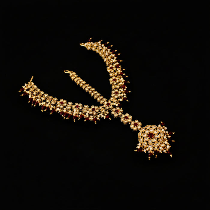 Ornate necklace with red stones on a dark background, featuring the brand 'Saheli'.