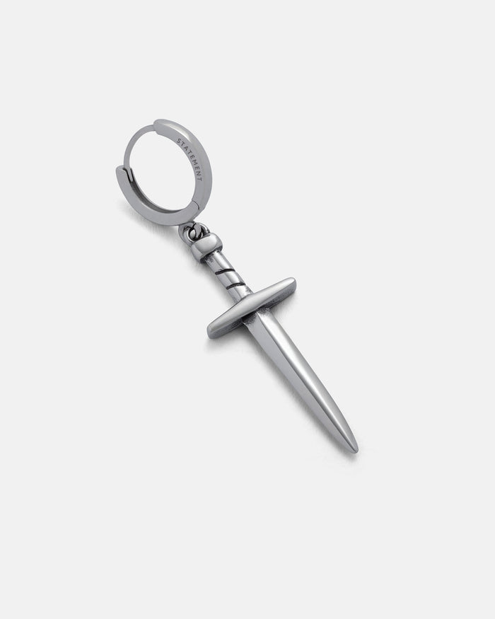 The Dagger Earring is a stainless steel silver hoop featuring a detailed hilt and pointed blade, creating an eye-catching statement piece. Displayed on a plain white background.
