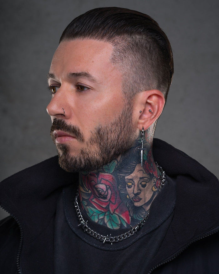 tattooed man wearing silver statement dagger earring