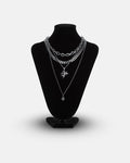 A black mannequin displays the Statement Collective Dead Love Set, a grunge necklace set featuring layered chains and pendants—including a striking skull heart pendant—against a plain white background.