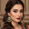 Ornate earrings with green and red accents on a dark background, branded 'SAHELLI'.