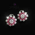Pair of earrings with pink and white gemstones on a gray background, featuring the brand 'Saheli'.