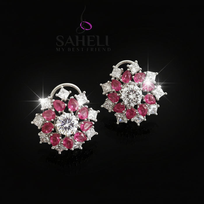 Pair of earrings with pink and white gemstones on a gray background, featuring the brand 'Saheli'.