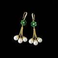 Pair of earrings with pearls and green gemstones on a dark background, branded 'SAHELI'.
